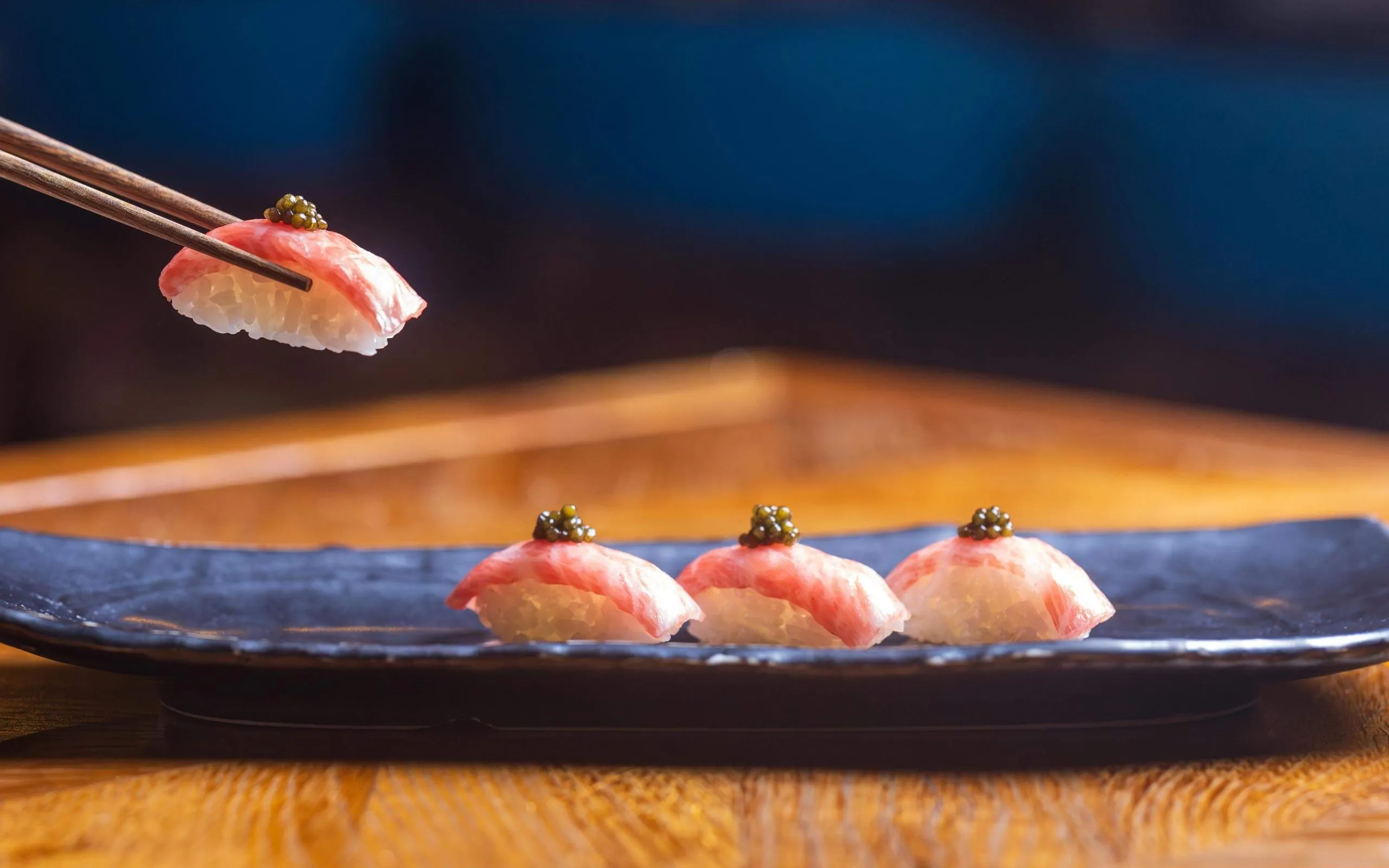 Nigiri lifted by chopsticks at the Kuuru Nikkei Bar